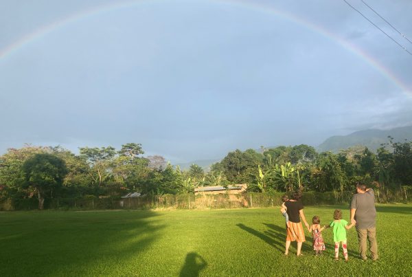 Family in a field viewing a rainbow.