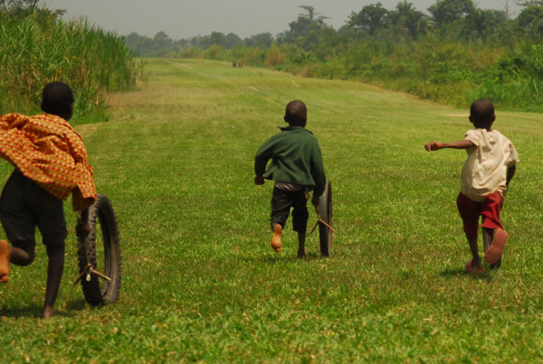 young boys running in a field in Uganda